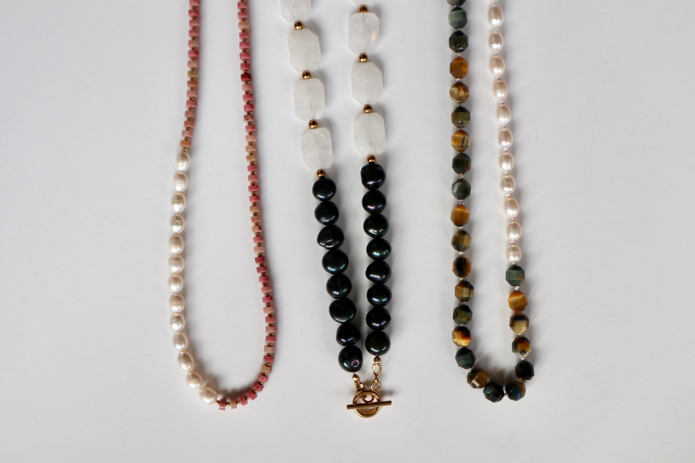 Handmade pearl and gemstone necklace collection by Auréad Designs including rhodonite, tiger eye, and freshwater pearl styles on white background