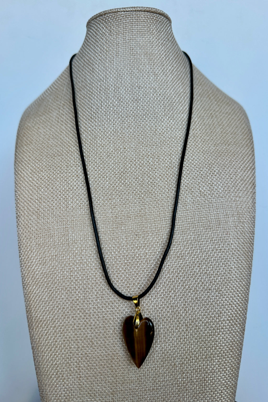 Ardene tiger eye heart pendant necklace by Auréad Designs on selenite slab, close-up showing black leather cord