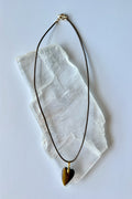 Ardene tiger eye heart pendant necklace by Auréad Designs on white selenite slab, bronze leather cord