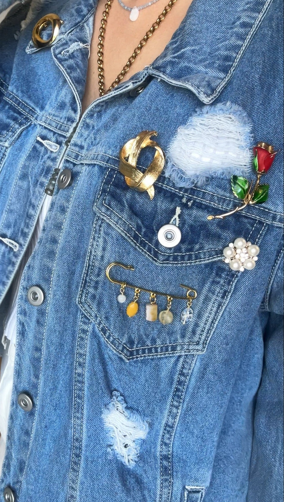 Auréad Designs Aurene gold kilt pin brooch styled with a collection of mixed brooches on a distressed blue denim jacket.