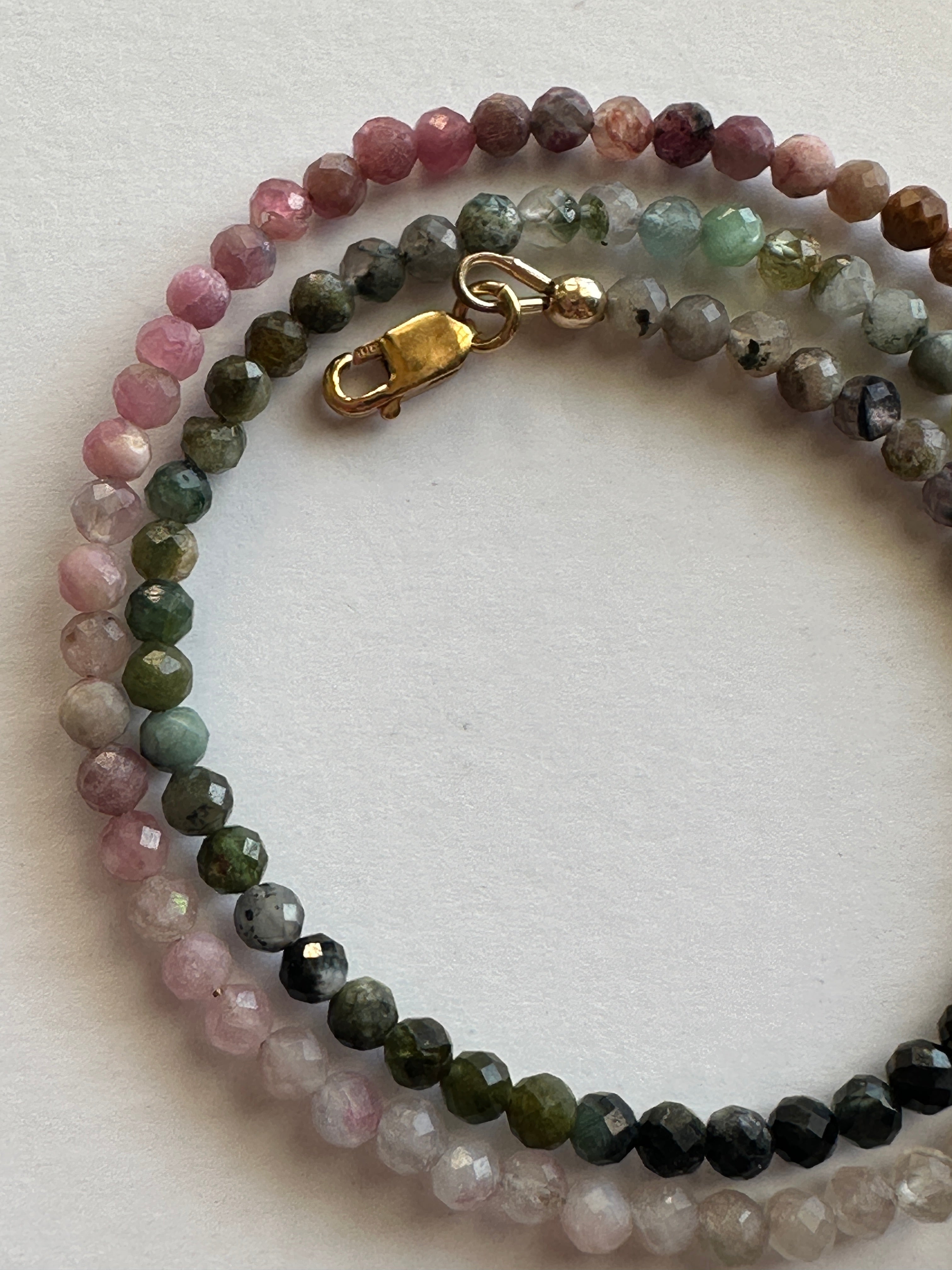 Close-up of the Aurora necklace showing the color gradient of multicolored micro-faceted tourmaline beads transitioning across the strand