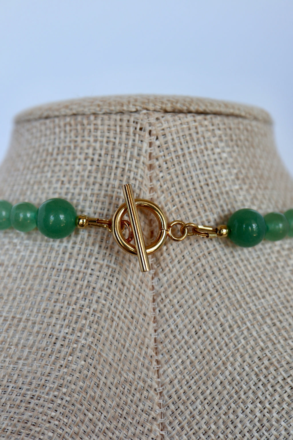 Close-up of Auréad Designs Aventine necklace gold toggle clasp with green aventurine beads on a linen bust form.