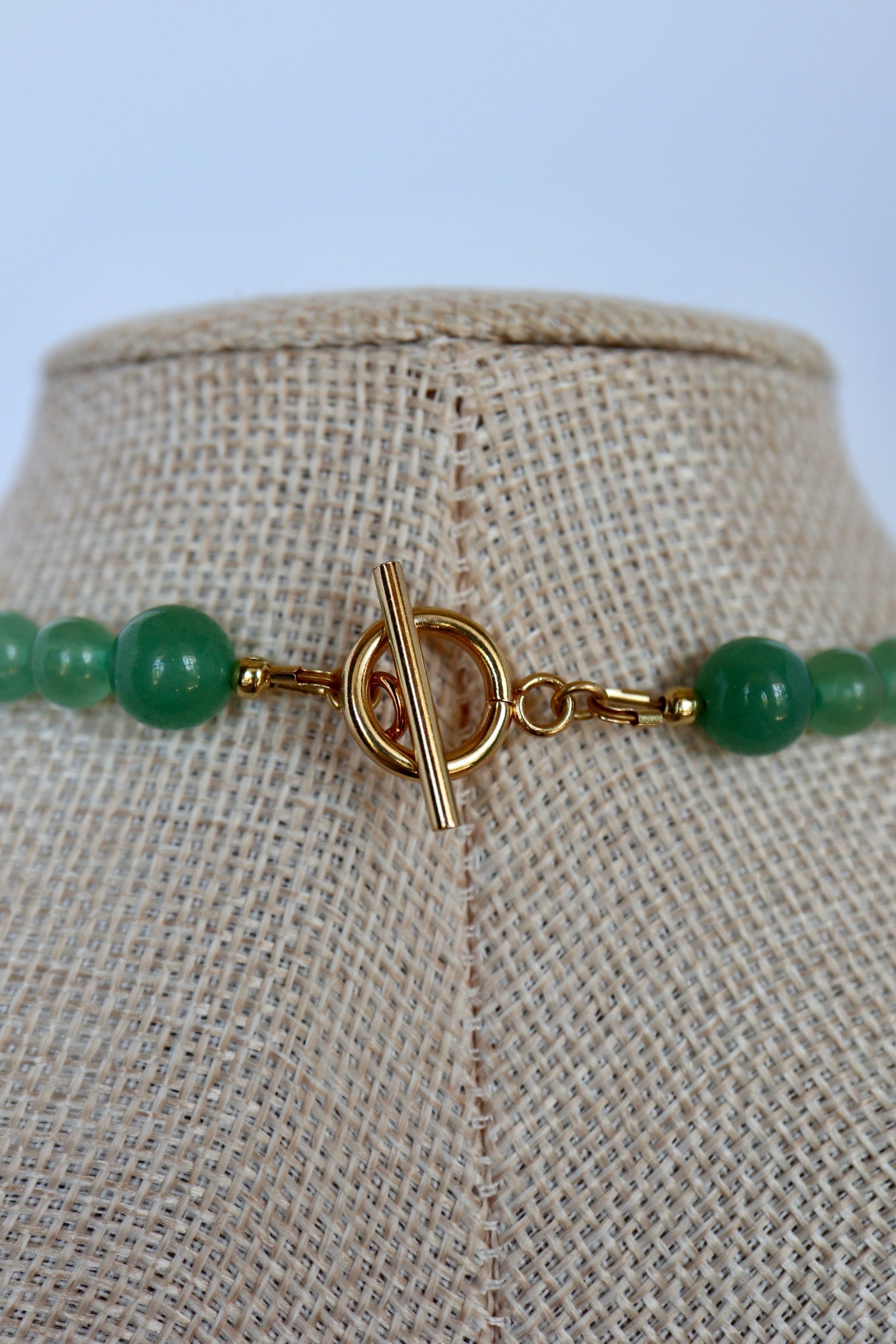 Close-up of Auréad Designs Aventine necklace gold toggle clasp with green aventurine beads on a linen bust form.