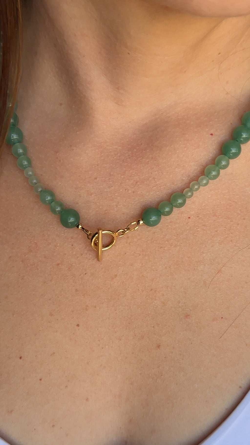 Auréad Designs Aventine green aventurine beaded necklace worn at the collarbone with gold toggle clasp visible, styled over a white top.