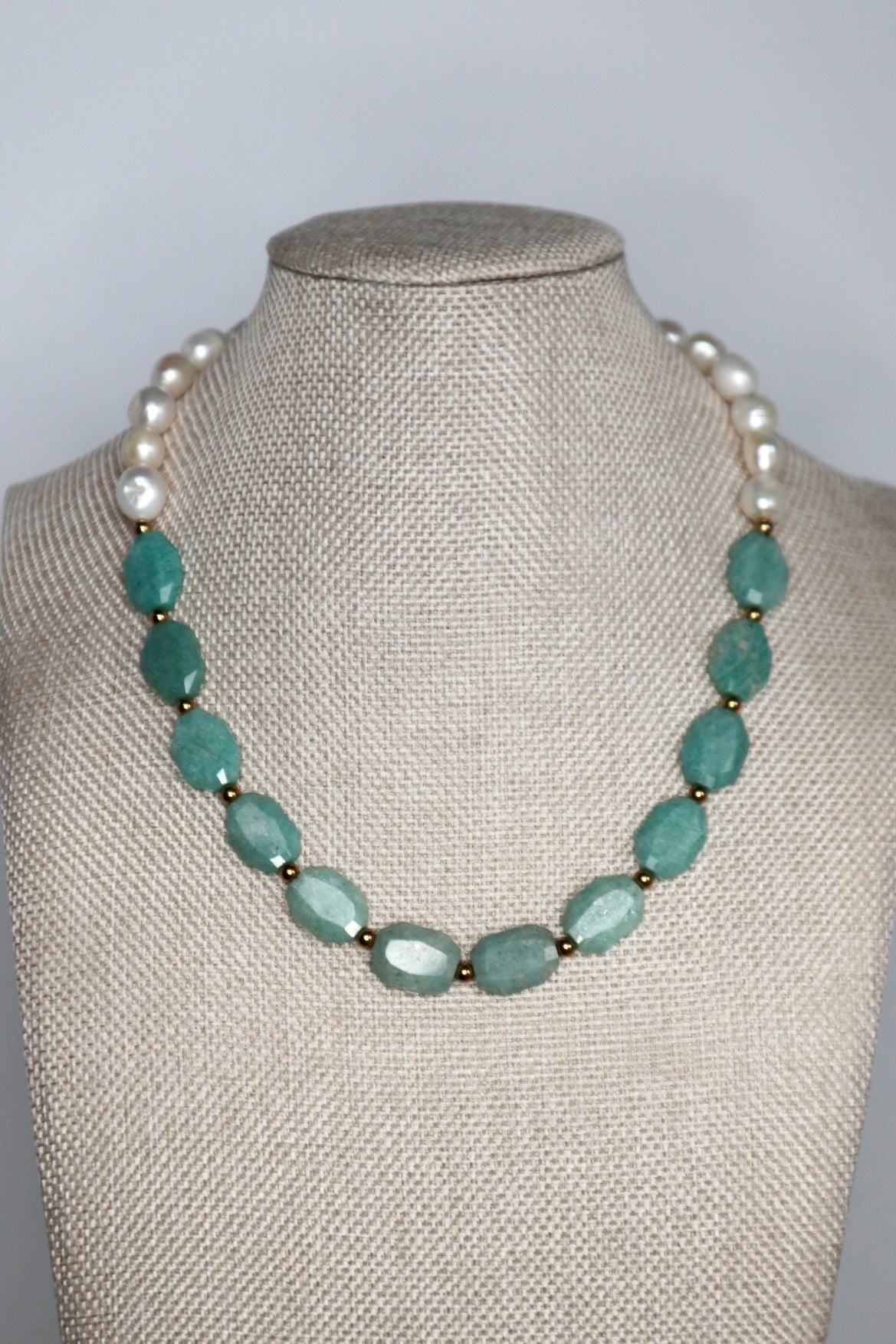Azurea Maren amazonite and freshwater pearl necklace by Auréád Designs displayed on a linen bust form, with faceted teal amazonite stones centered at the front and large baroque freshwater pearls framing the shoulders