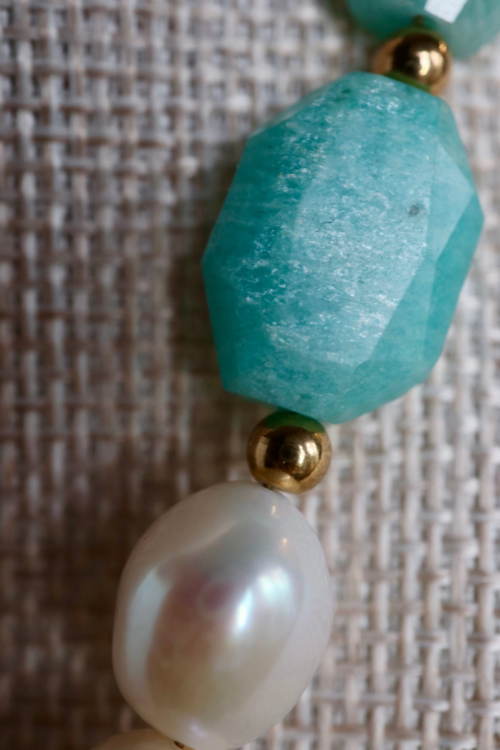  Close-up detail of the Azurea Maren necklace by Auréád Designs, showing a large faceted teal amazonite bead and baroque freshwater pearl separated by a gold accent bead