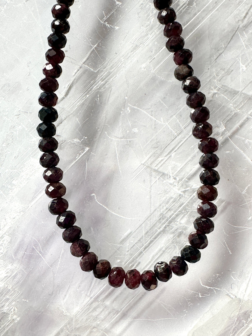 Close-up of the Brenna necklace showing the deep red tones and delicate faceting of the garnet gemstone beads catching the light with subtle movement