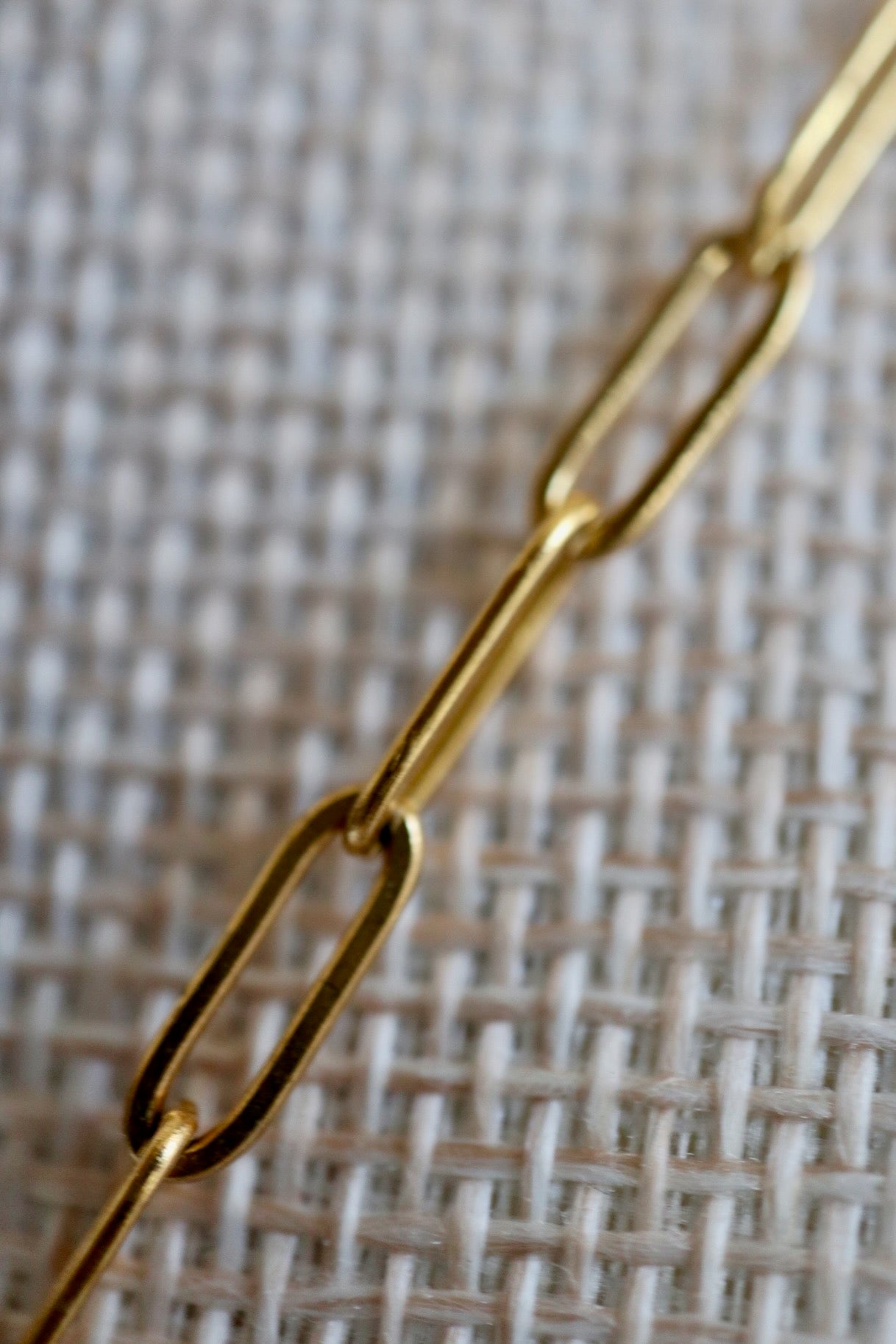Auréad Designs Caelova lariat necklace close-up of gold stainless steel paperclip chain links on linen bust form