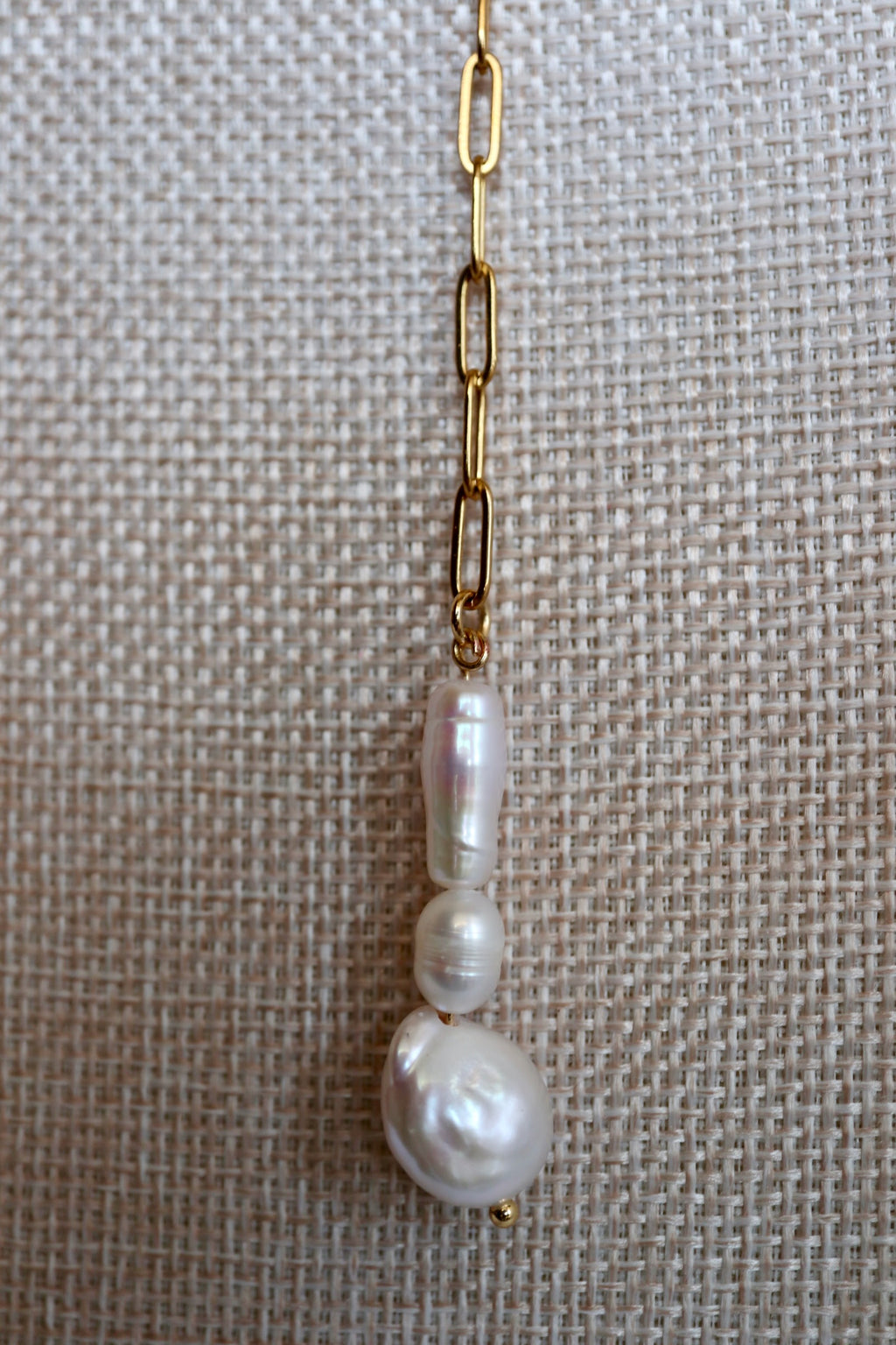 Auréad Designs Caelova lariat necklace close-up of wire-wrapped triple freshwater pearl pendant showing baroque keshi, flat round, and rice pearl shapes hanging from gold paperclip chain link