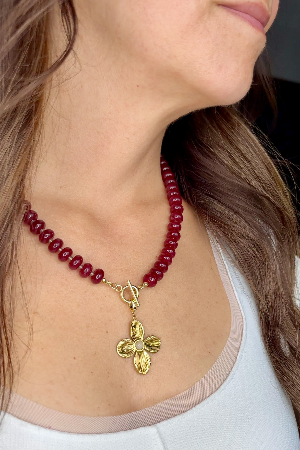 Carmina red jade necklace by Auréad Designs, worn with toggle clasp in front and flower pendant