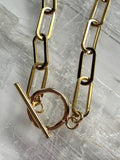 Close-up of the Catenne necklace showing the elongated 18k gold PVD stainless steel paperclip chain links and toggle clasp