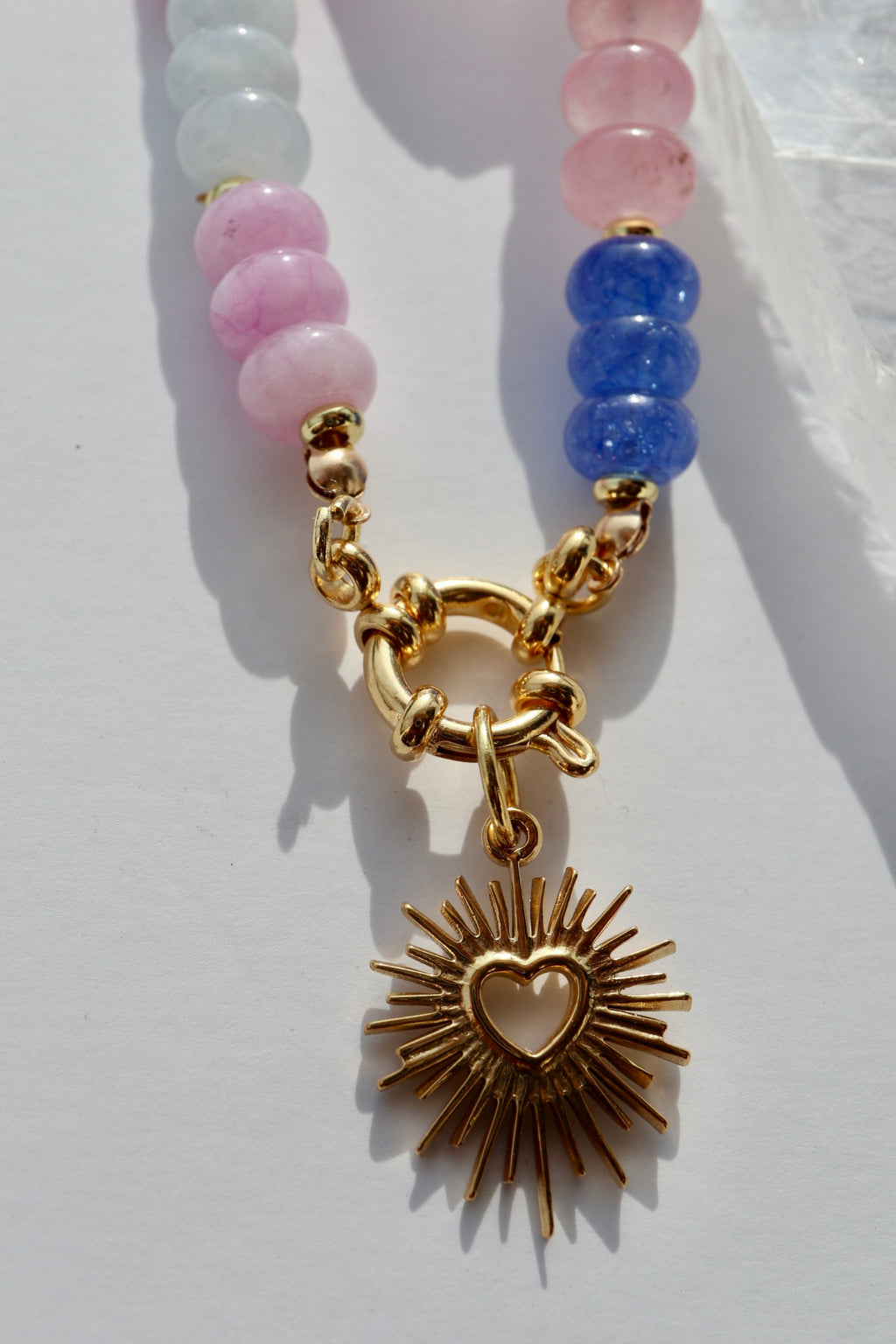 Close-up of the Cherise necklace showing the gold stainless steel radiant heart pendant against the colorful pink and purple jade rondelle beads