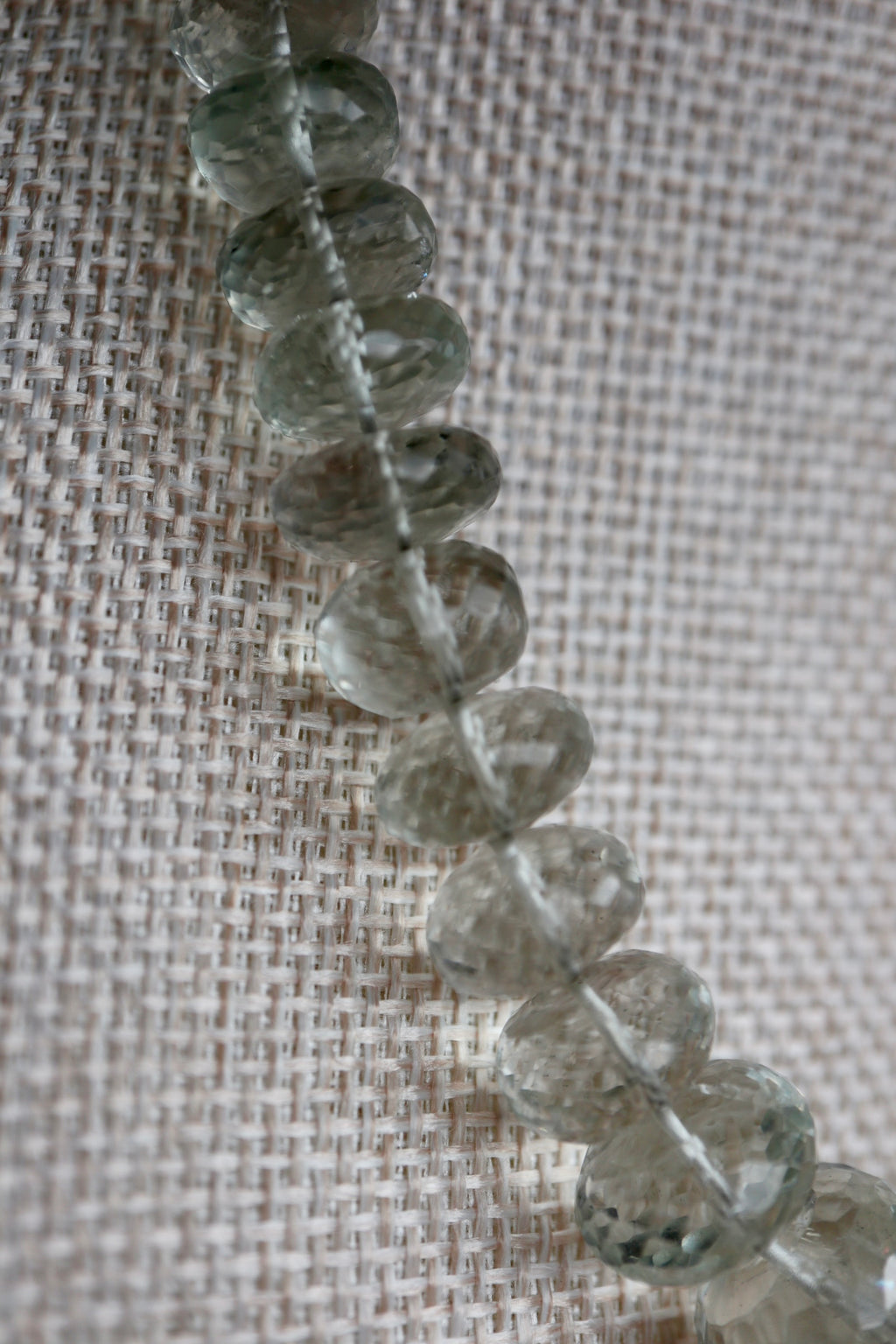 Macro close-up of the Clarae necklace showing the individual facets and soft translucent green tones of the graduated green quartz gemstone beads