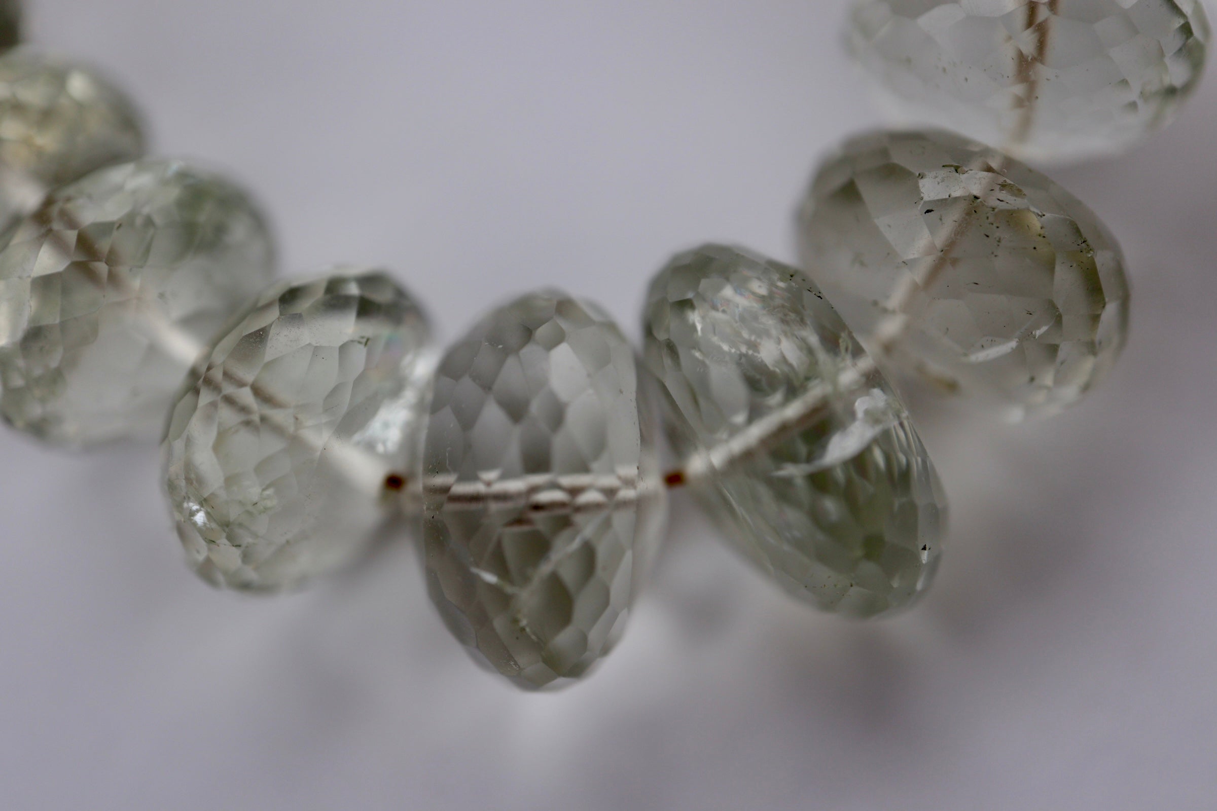 Macro close-up of the Clarae necklace showing the intricate faceting and natural translucency of the graduated green quartz gemstone beads with their subtle inclusions and soft green tones