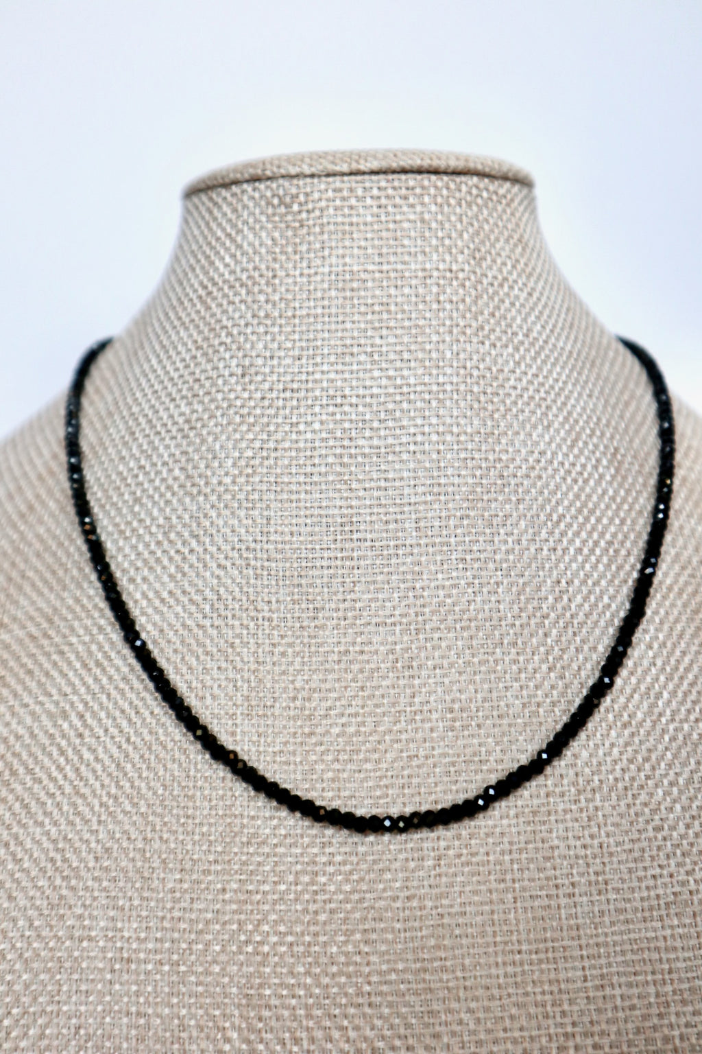 Auréad Designs Corvine necklace displayed front-facing on linen bust form, continuous strand of faceted black spinel beads sitting at collarbone length