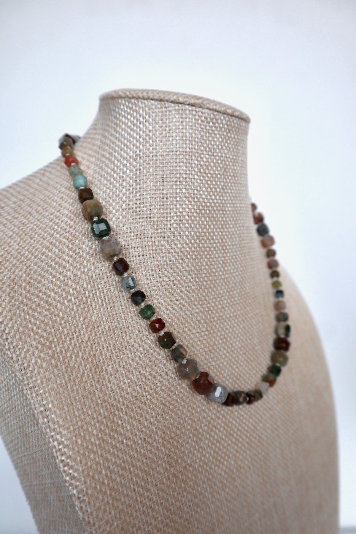 Current necklace by Auréad Designs displayed on a linen bust, full-length view of the silk-knotted indian agate beads in multicolored natural tones