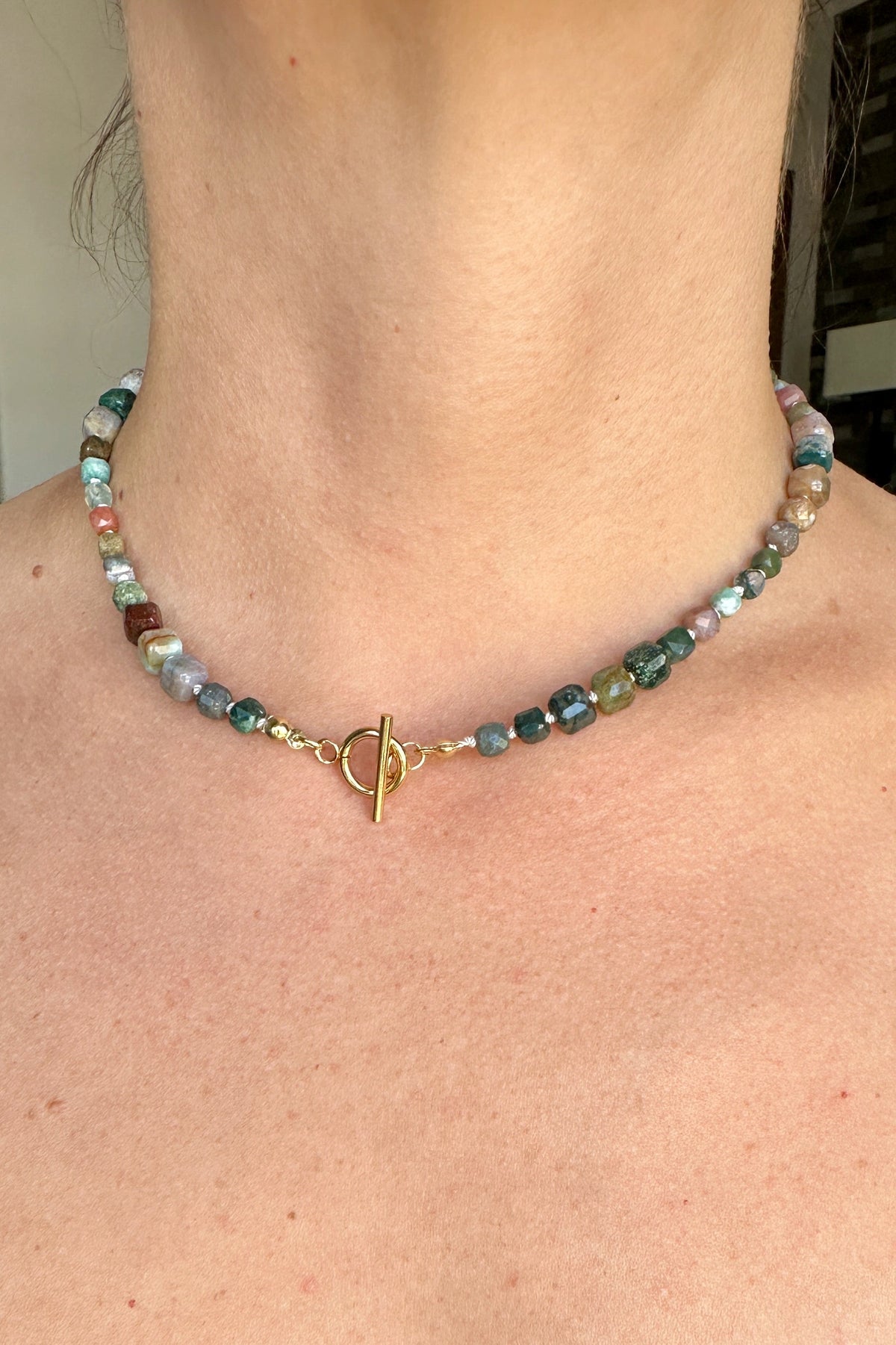 Current necklace by Auréad Designs worn at the neck, handmade indian agate beads in natural red, green, and brown tones with a gold toggle clasp, from the Glacier Collection
