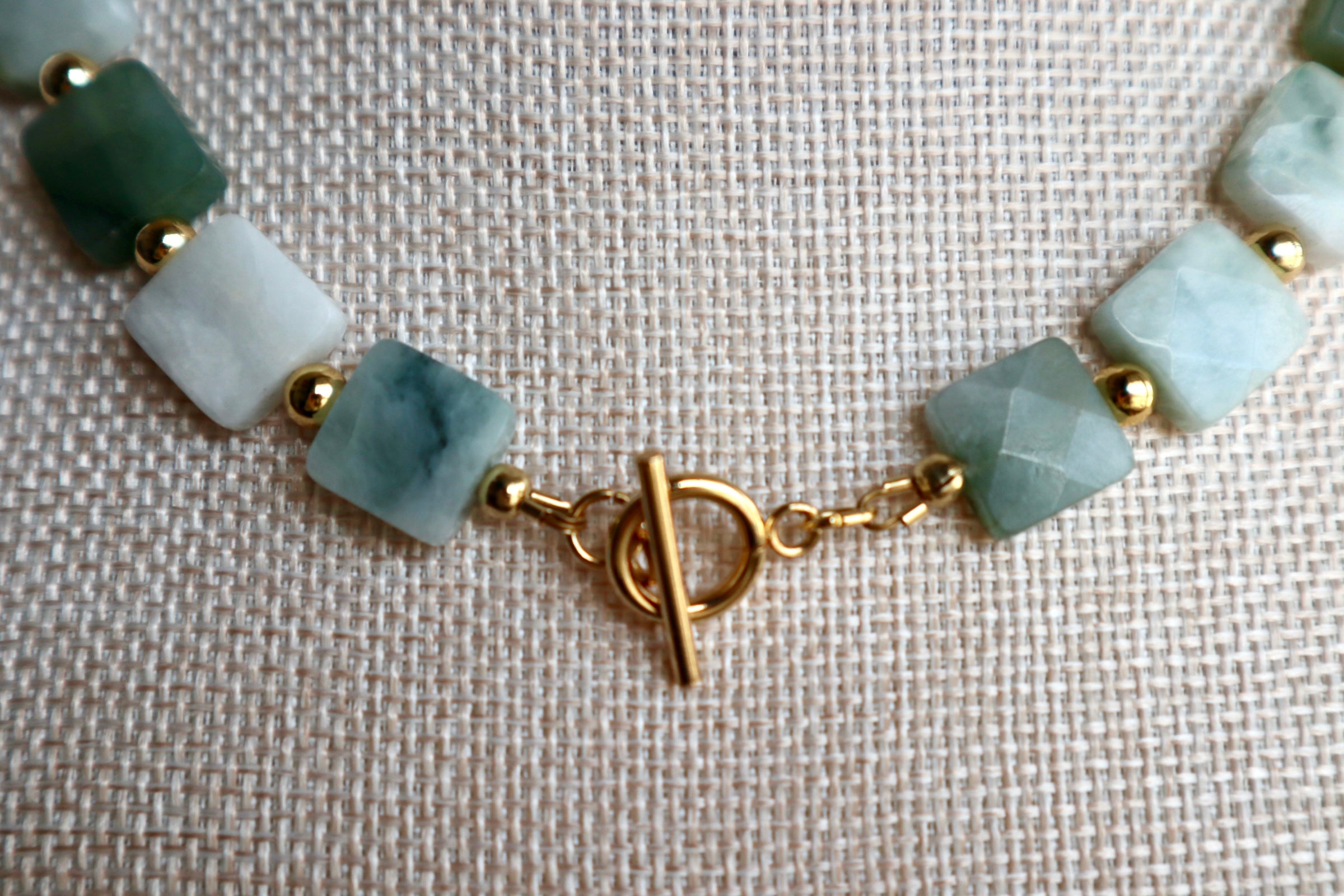 Close-up of the Everra necklace showing the geometric square nephrite jade beads and gold stainless steel toggle clasp with warm gold spacer beads