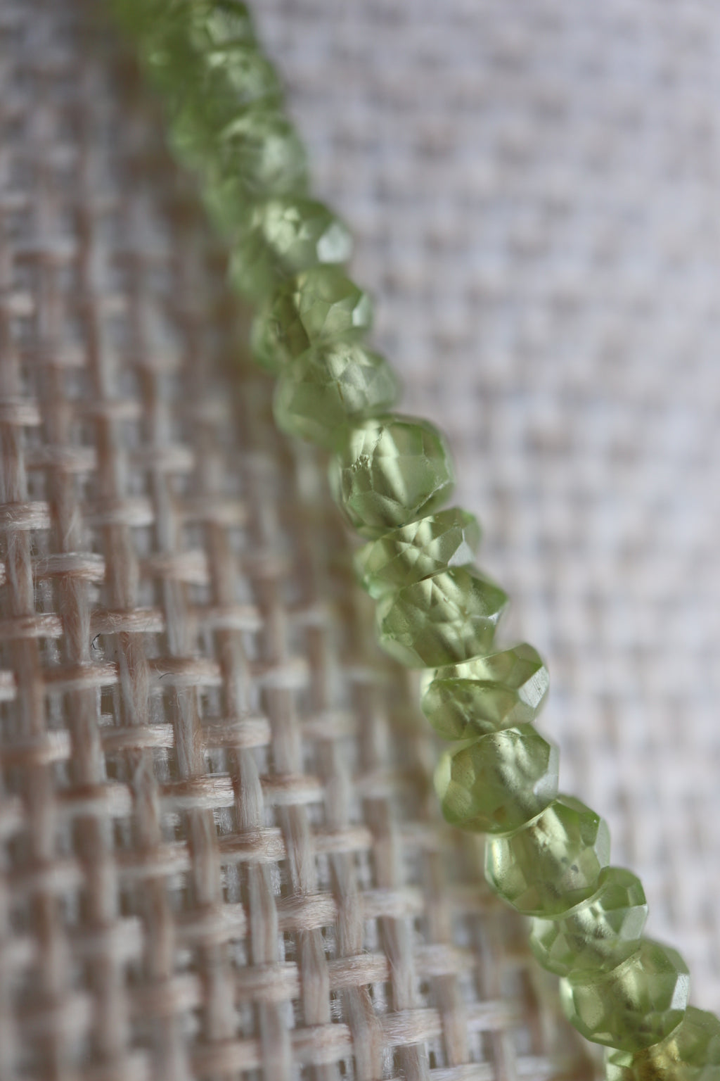 Close-up of the Florae necklace highlighting the vibrant green glow and faceting of the peridot gemstone beads alongside the gold-filled cable chain