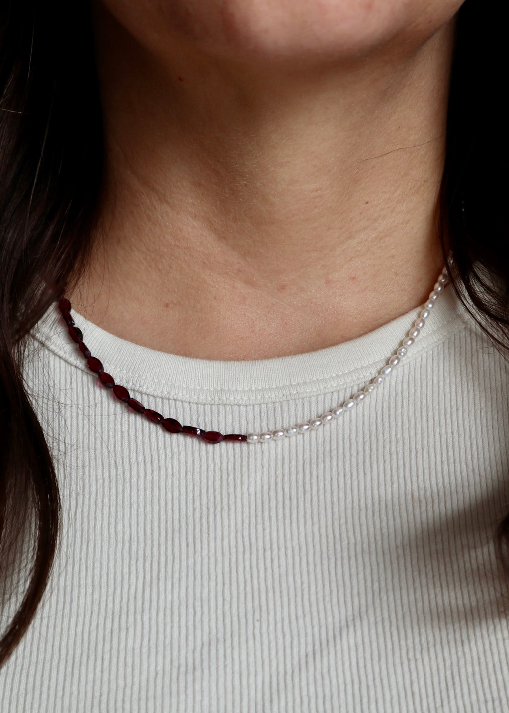 Garnelle garnet and freshwater pearl necklace worn at the collarbone, front view, showing the rich red garnet beads and pearl accents against skin