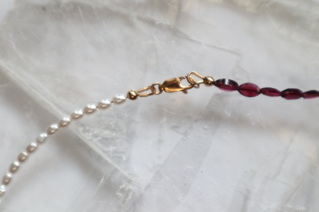 Detail shot of the Garnelle necklace highlighting the contrast between deep red marquise garnet beads and soft freshwater pearls with the gold-filled clasp