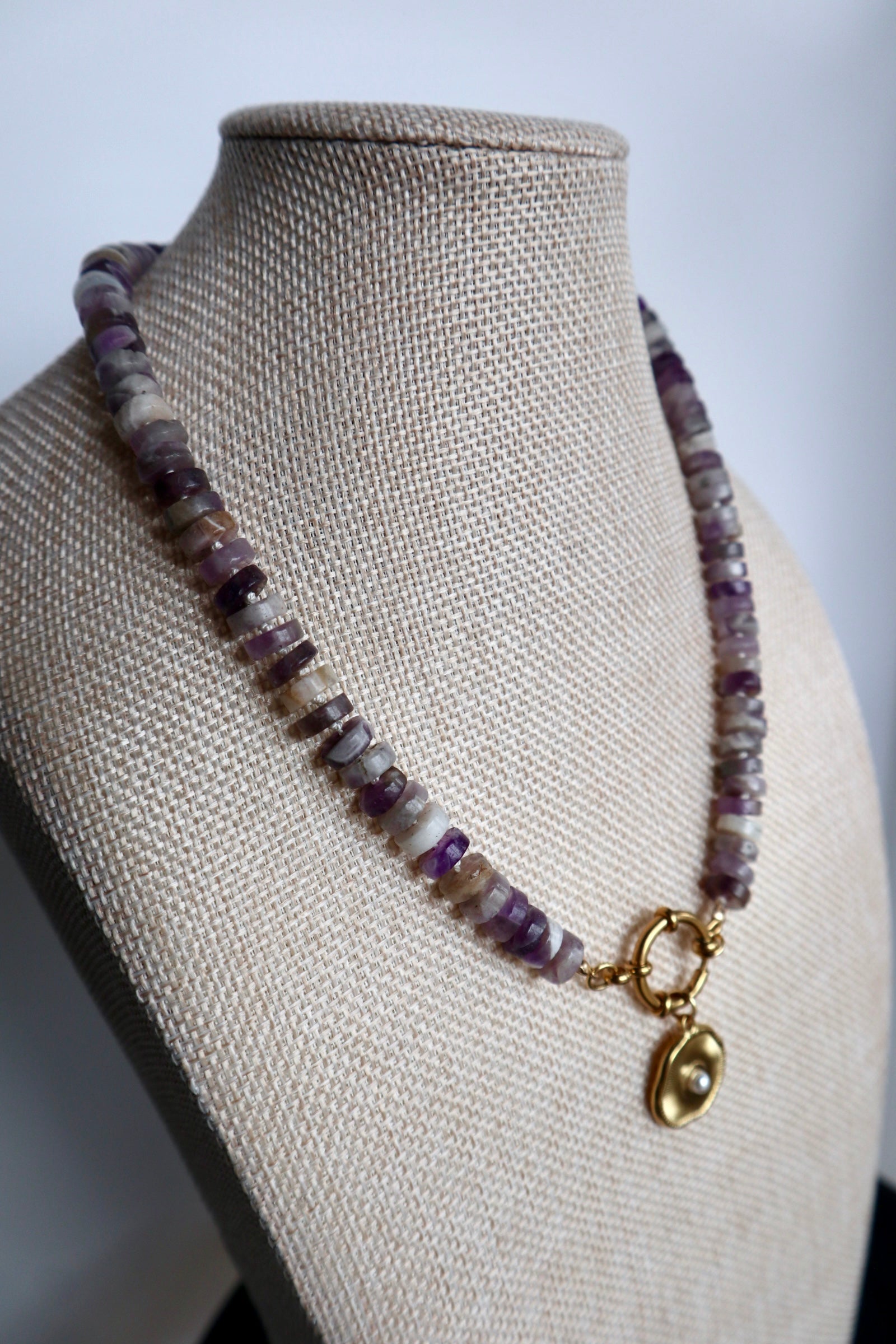 Isolde amethyst silk-knotted necklace by Auréad Designs on a linen bust form, highlighting the rich purple tones of the amethyst heishi beads and the delicate cream silk hand-knotting