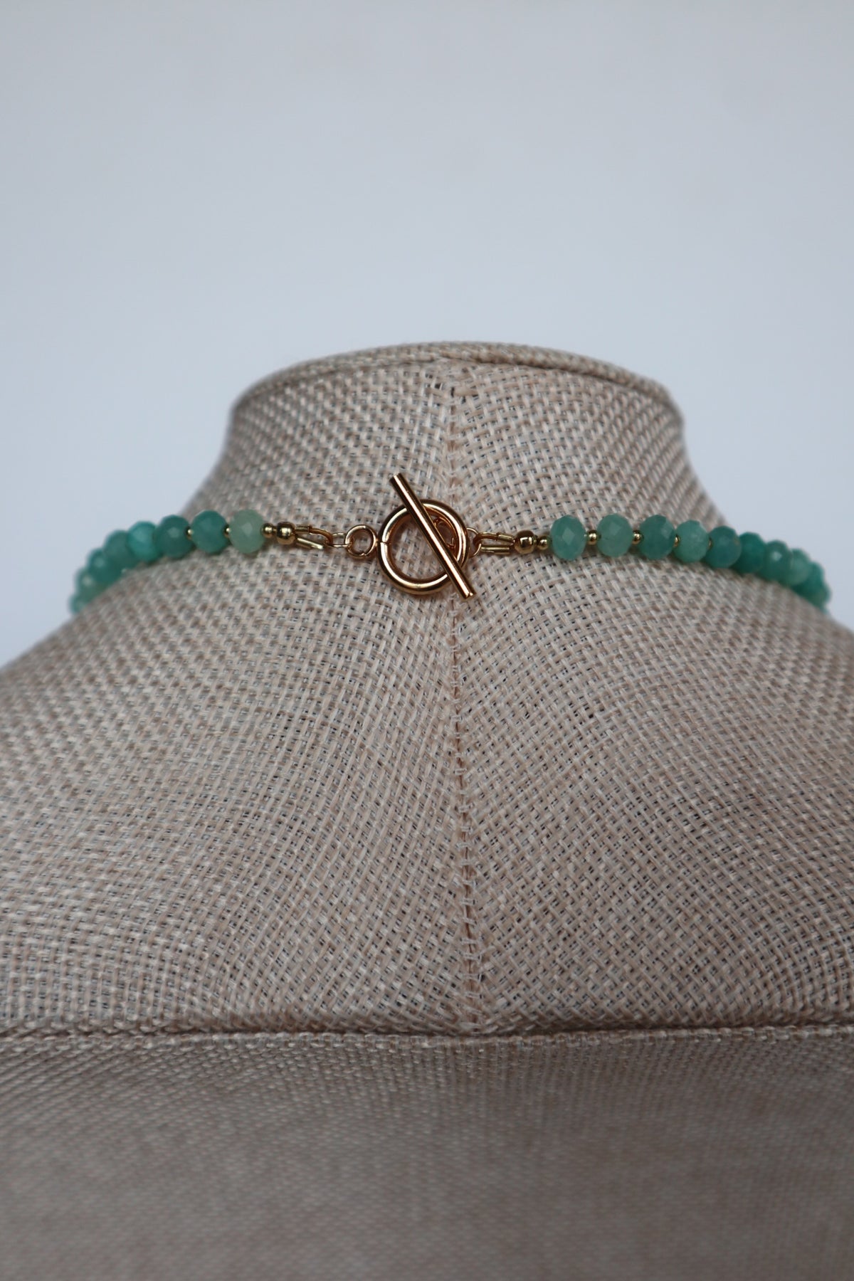 Close-up of the gold toggle clasp on the Lake necklace by Auréad Designs, with amazonite rondelles and gold spacer beads on either side