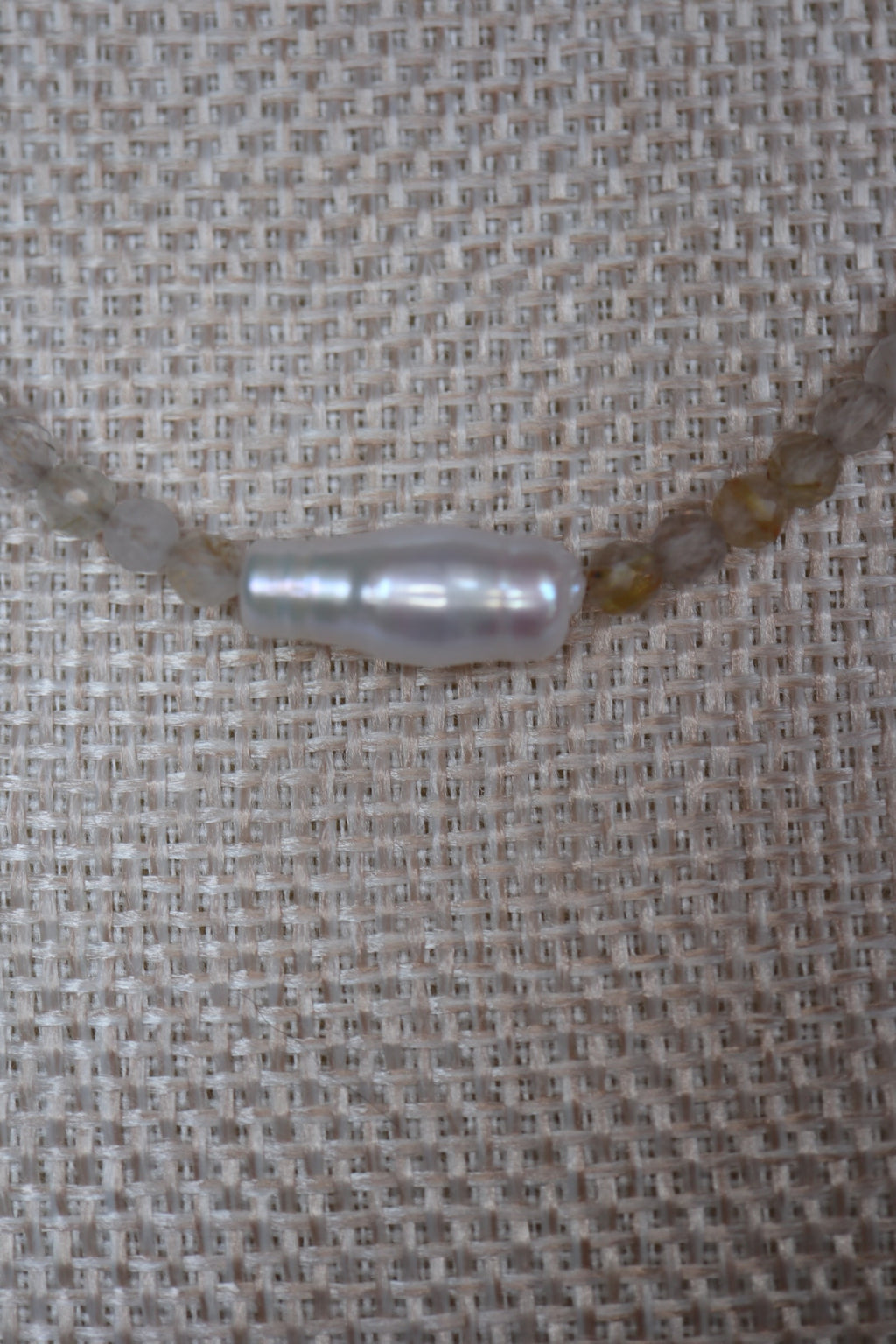 Close-up of the single baroque freshwater pearl focal bead on the Larch necklace by Auréad Designs, centered among faceted golden rutilated quartz beads