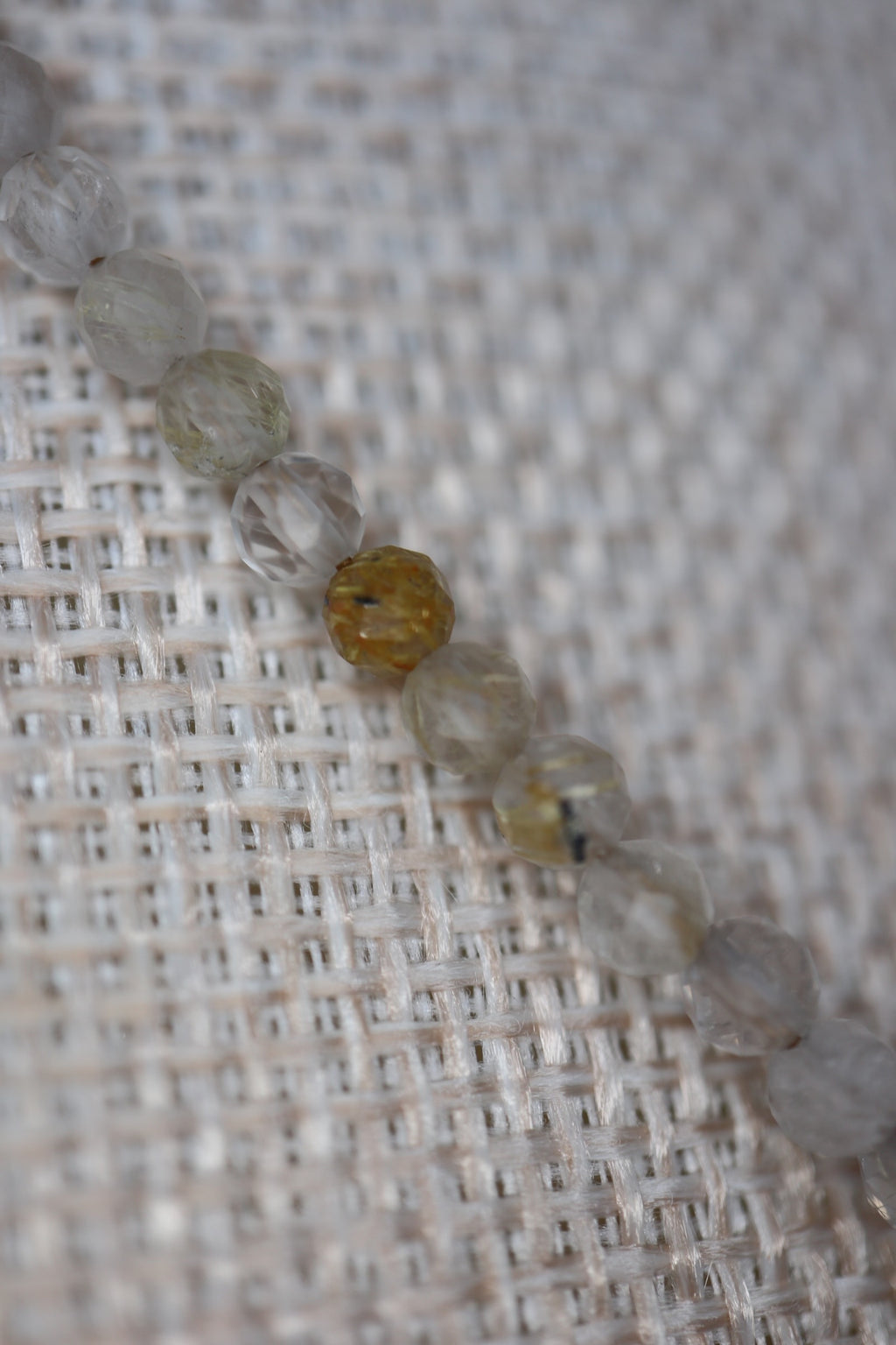 Close-up of faceted golden rutilated quartz beads on the Larch necklace by Auréad Designs, showing the natural golden rutile inclusions and warm clarity of each stone
