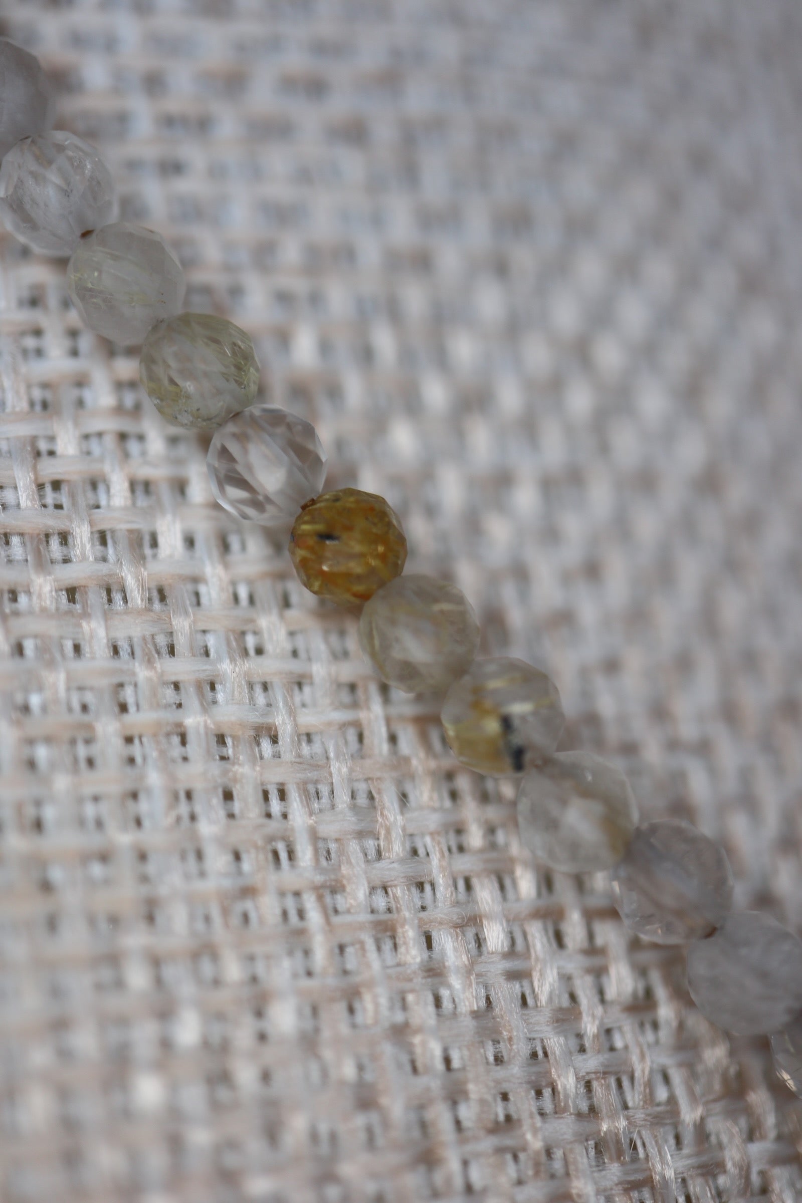 Close-up of faceted golden rutilated quartz beads on the Larch necklace by Auréad Designs, showing the natural golden rutile inclusions and warm clarity of each stone