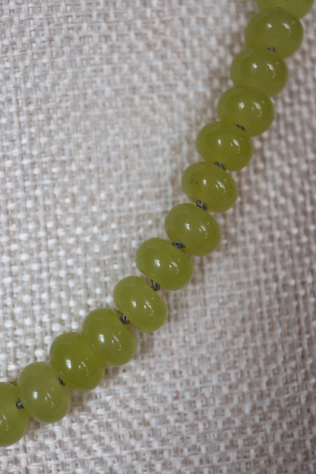 Close-up of silk-knotted lemon jade rondelle beads on the Ledge necklace by Auréad Designs, showing the smooth vivid yellow-green stone and individual silk knots between each bead