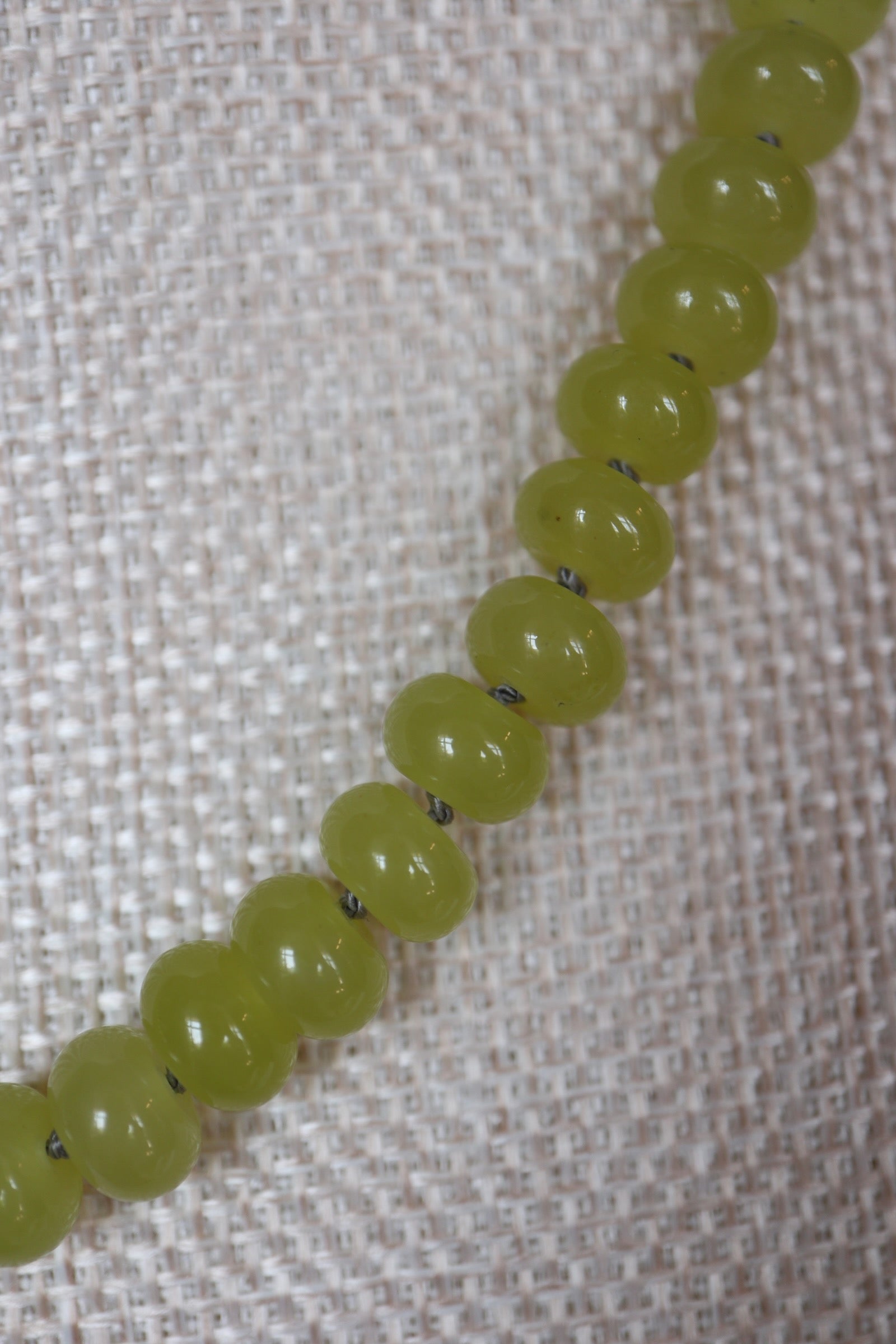 Close-up of silk-knotted lemon jade rondelle beads on the Ledge necklace by Auréad Designs, showing the smooth vivid yellow-green stone and individual silk knots between each bead
