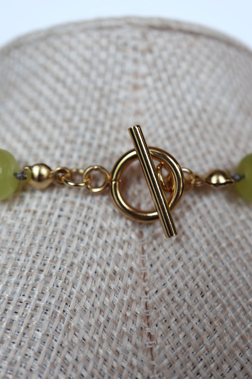 Close-up of the gold toggle clasp on the Ledge necklace by Auréad Designs, with lemon jade rondelle beads on either side