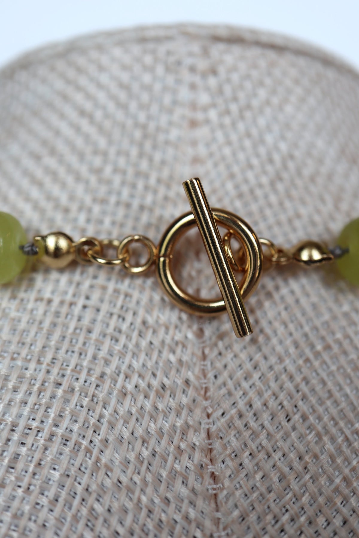 Close-up of the gold toggle clasp on the Ledge necklace by Auréad Designs, with lemon jade rondelle beads on either side