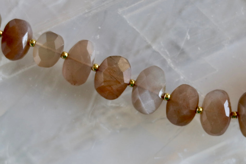 Close-up of the Lucent necklace highlighting the soft shimmer and warm glow of peach moonstone gemstone beads with gold-filled spacers