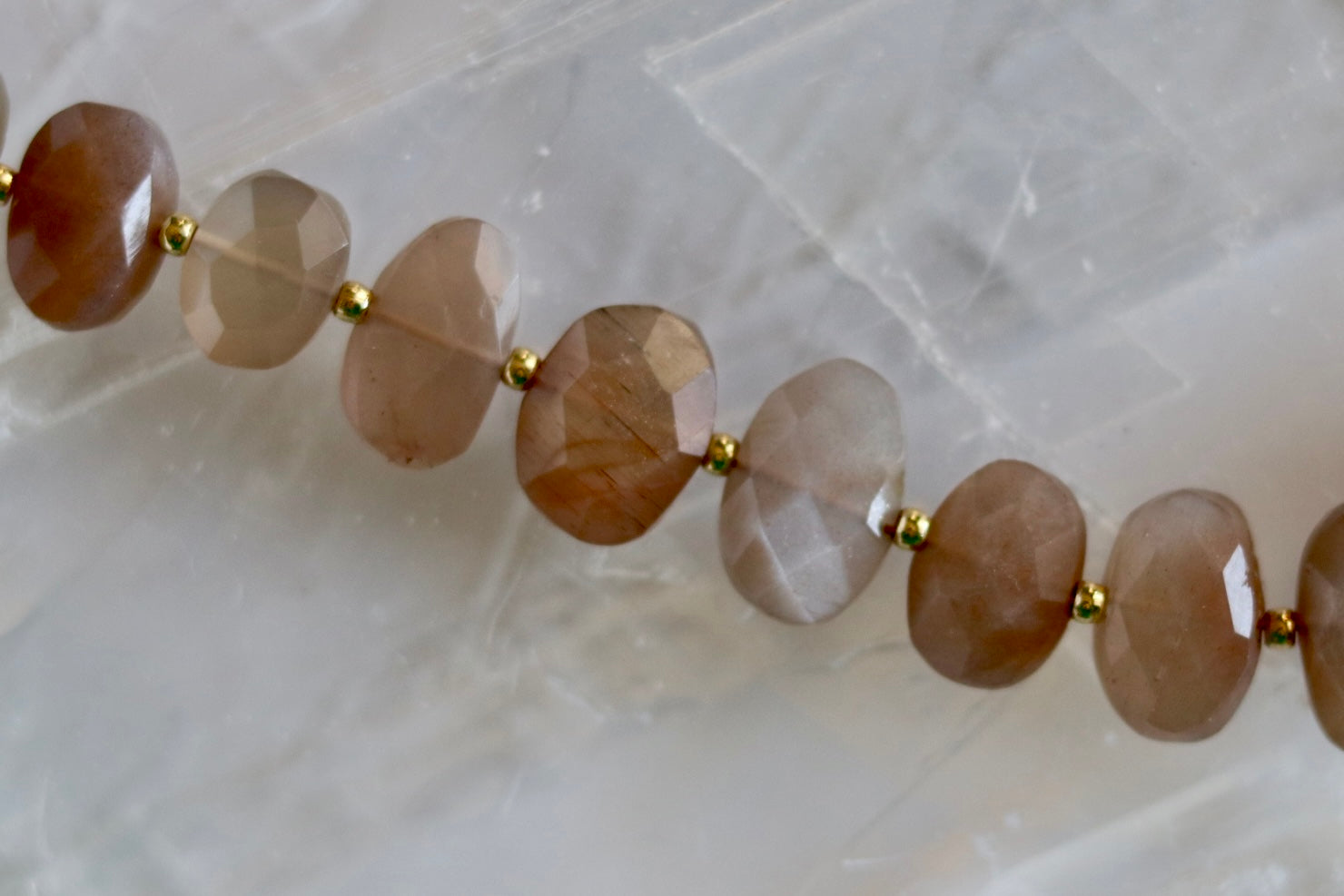 Close-up of the Lucent necklace highlighting the soft shimmer and warm glow of peach moonstone gemstone beads with gold-filled spacers