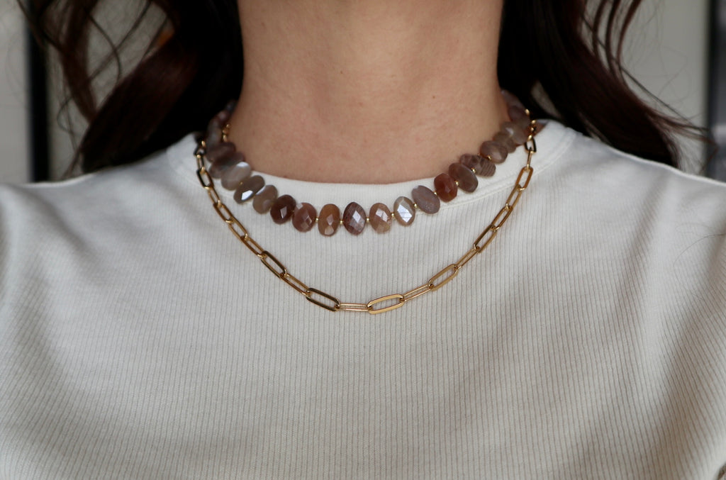 Lucent necklace by Auréad Designs worn on model, showing the peach moonstone bead strand layered with the a gold paperclip chain
