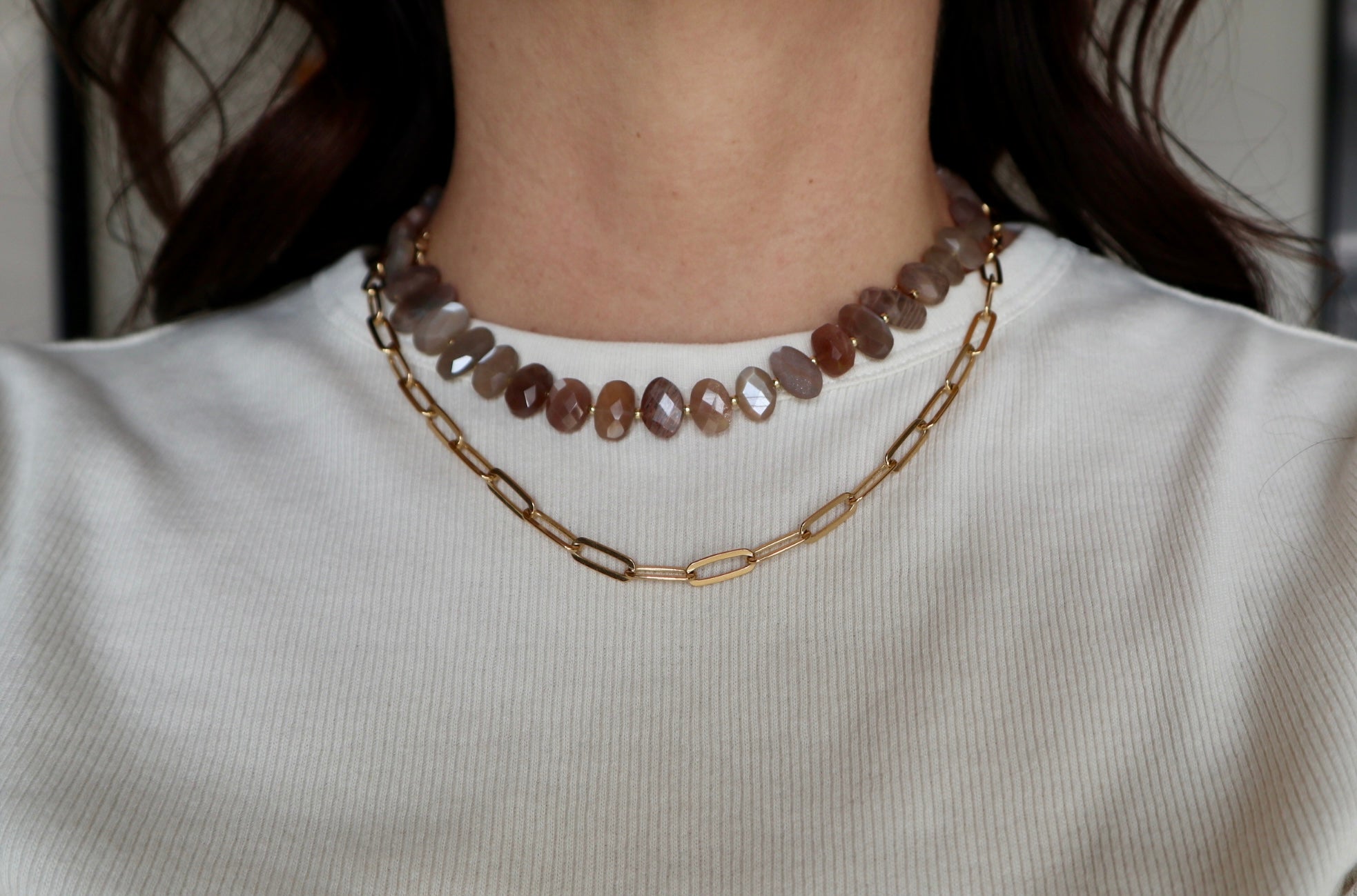 Lucent necklace by Auréad Designs worn on model, showing the peach moonstone bead strand layered with the a gold paperclip chain