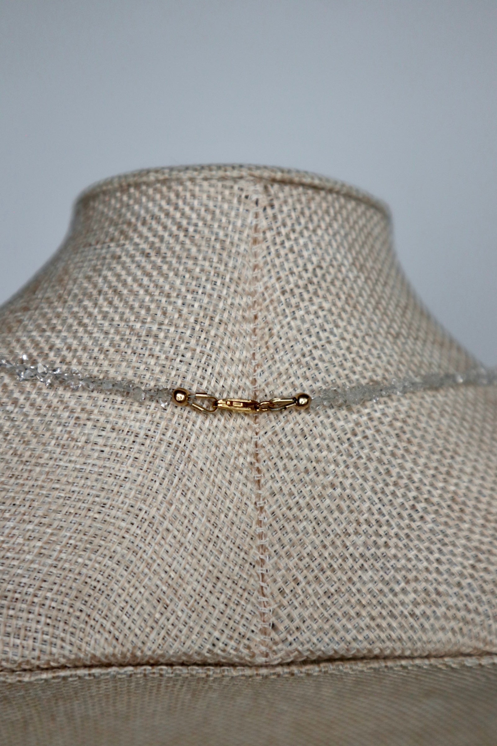 Close-up of the 14k gold-filled clasp on the Lumenne herkimer diamond chip necklace by Auréád Designs, displayed on a linen bust form