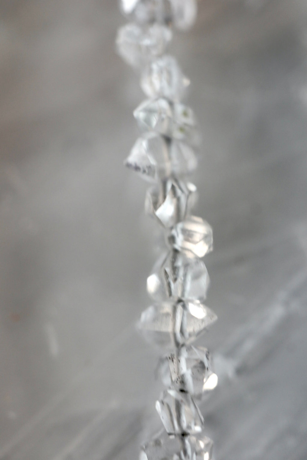 Close-up detail of the Lumenne necklace by Auréád Designs, showing the faceted herkimer diamond chips catching light against a soft grey background