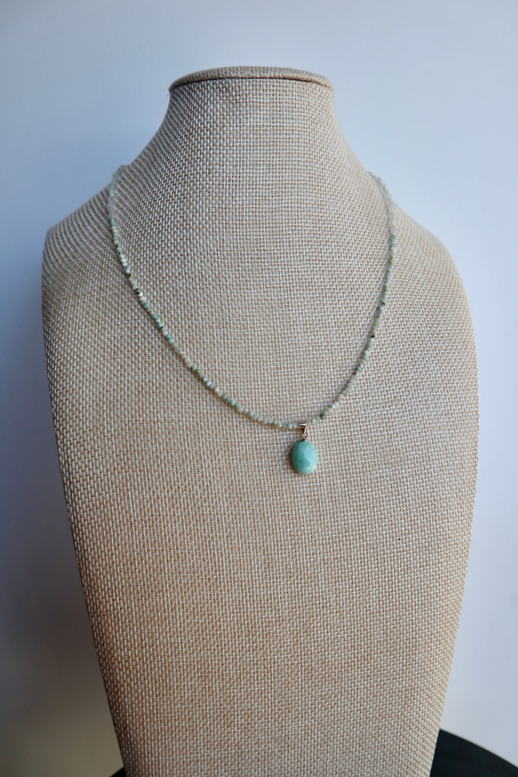 Lunamar necklace by Auréad Designs displayed on a linen bust form, showing the full strand of larimar and rainbow moonstone beads with the larimar pendant as a focal point