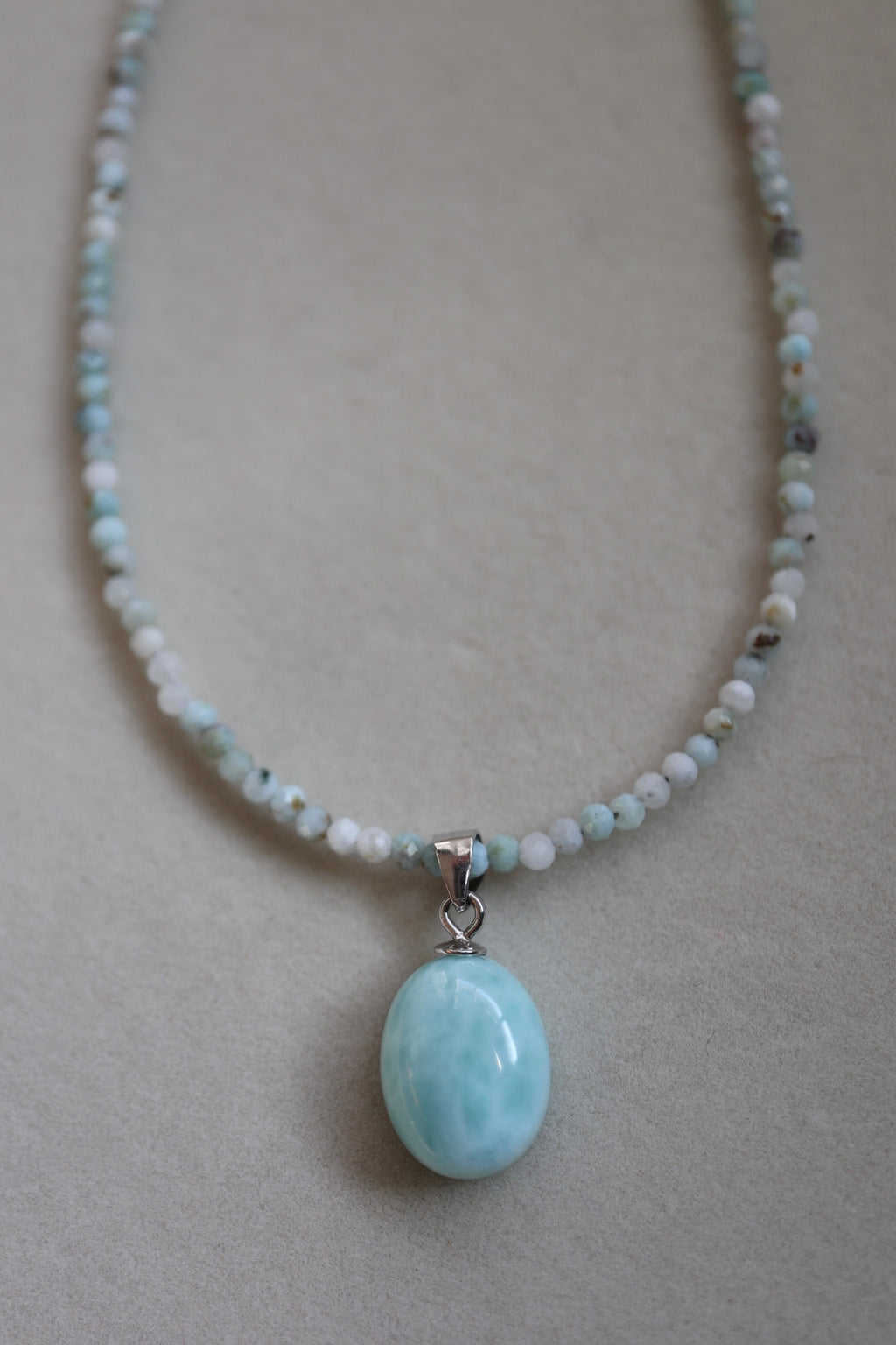 Lunamar necklace by Auréad Designs displayed on a neutral background, showing the micro-faceted larimar and beads with the smooth oval larimar pendant and sterling silver bail