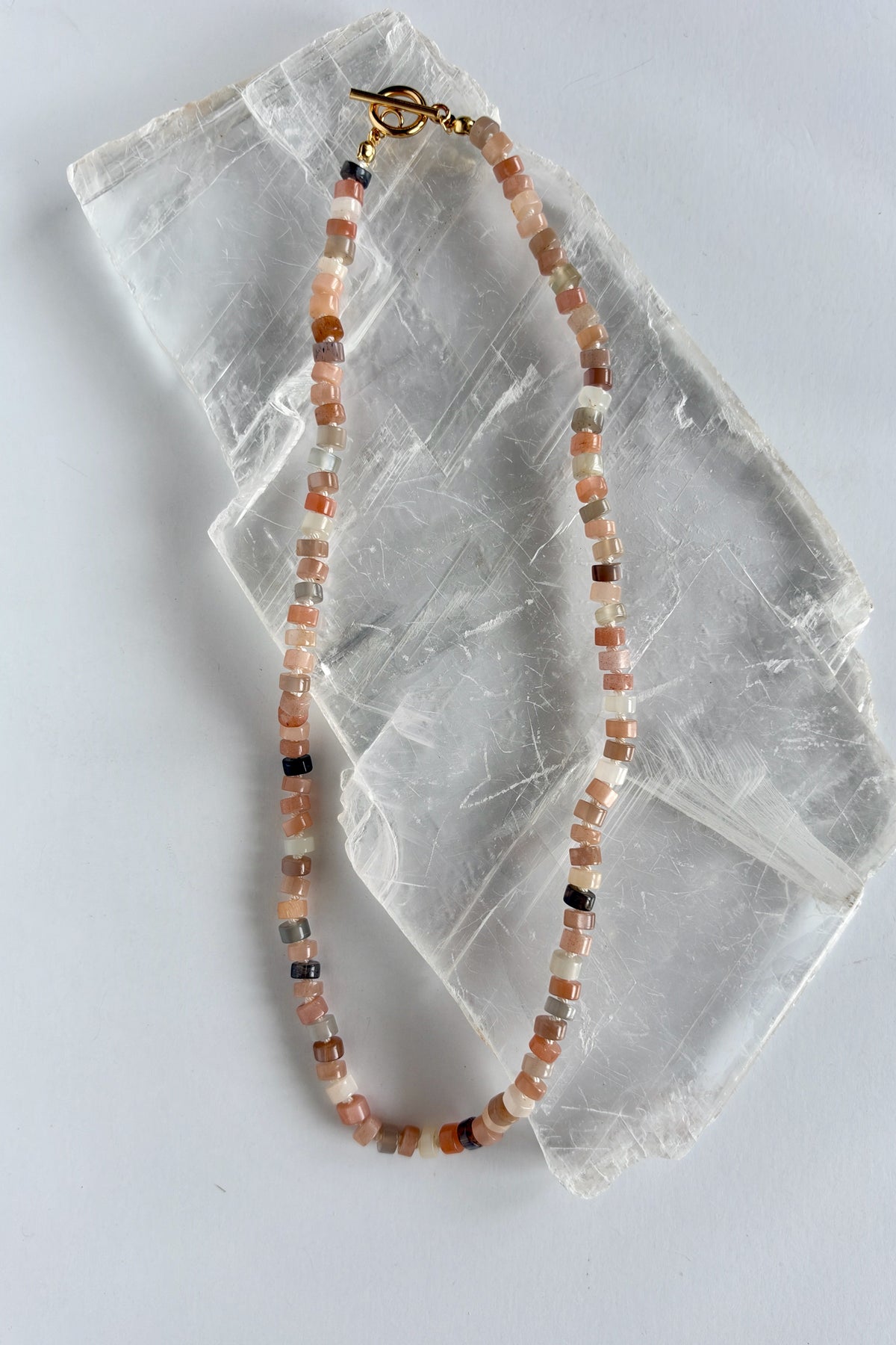 Maeven moonstone heishi necklace by Auréad Designs full length flat lay on white selenite