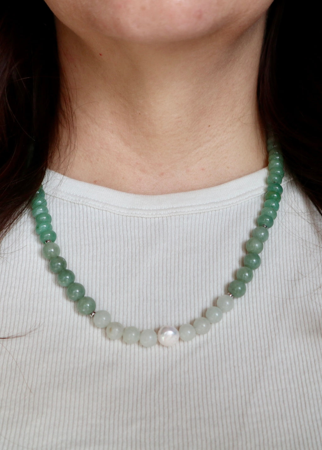 Close-up of the Meadowe necklace resting at the collarbone, highlighting the soft green and lavender tones of jade and grape agate beads with the luminous freshwater pearl against skin