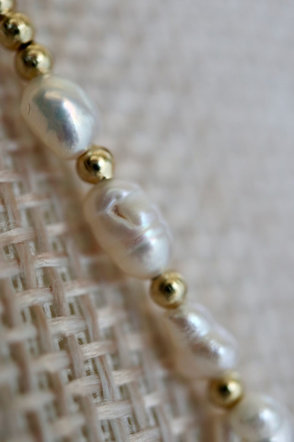 Auréad Designs Melline necklace close-up showing freshwater rice pearl luster and gold stainless steel micro spacer beads, photographed on linen bust form