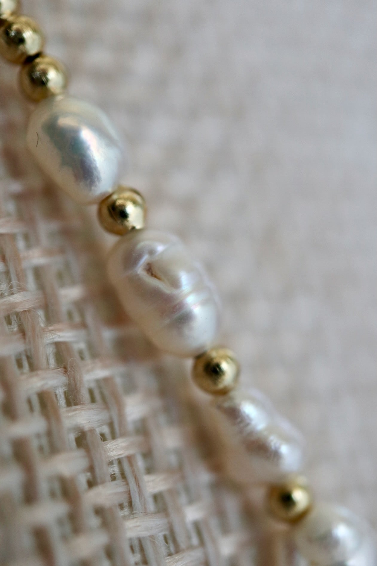 Auréad Designs Melline necklace close-up showing freshwater rice pearl luster and gold stainless steel micro spacer beads, photographed on linen bust form