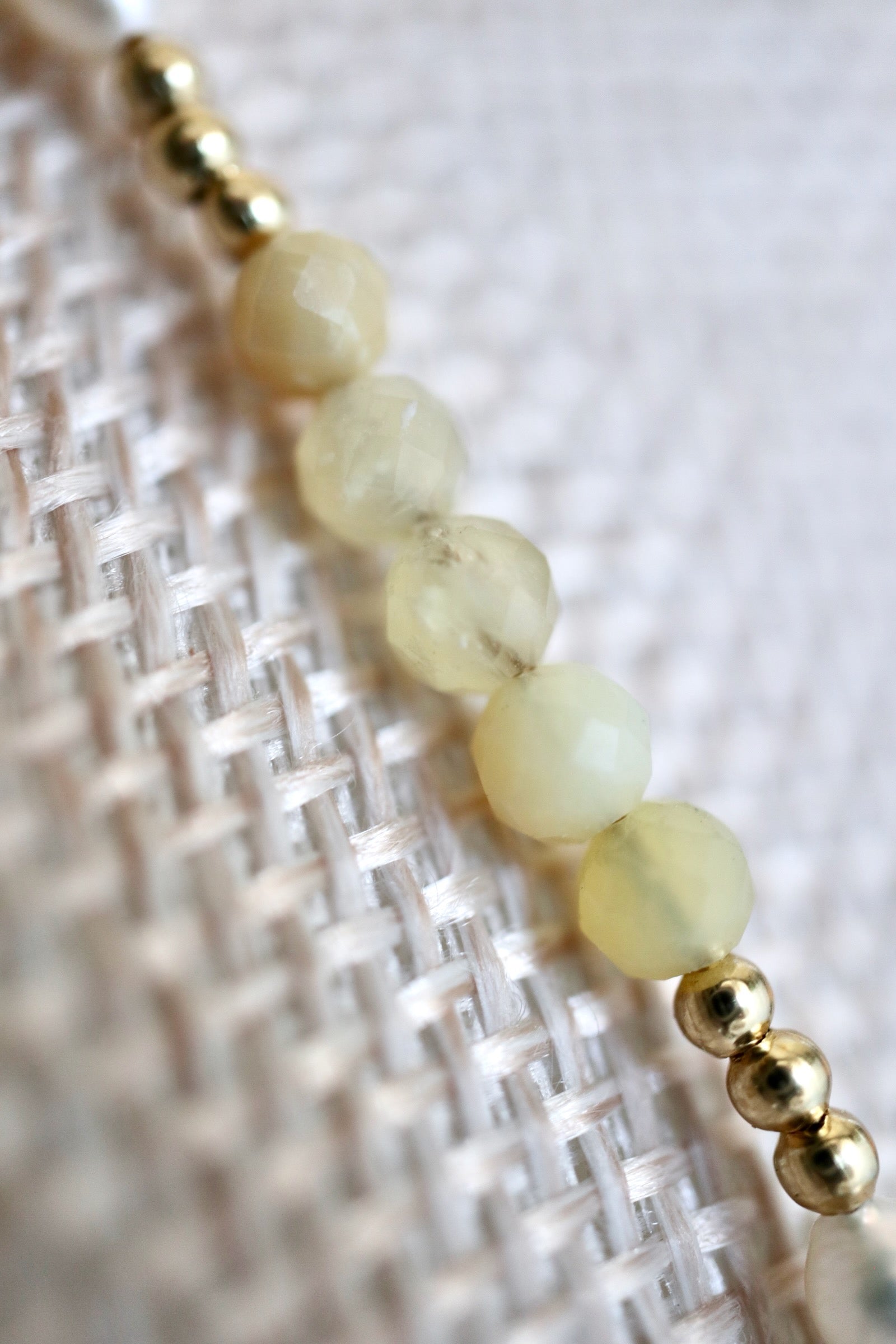Auréad Designs Melline necklace close-up of yellow opal beads showing translucent warm green-yellow tones, photographed on linen bust form with gold spacer beads visible