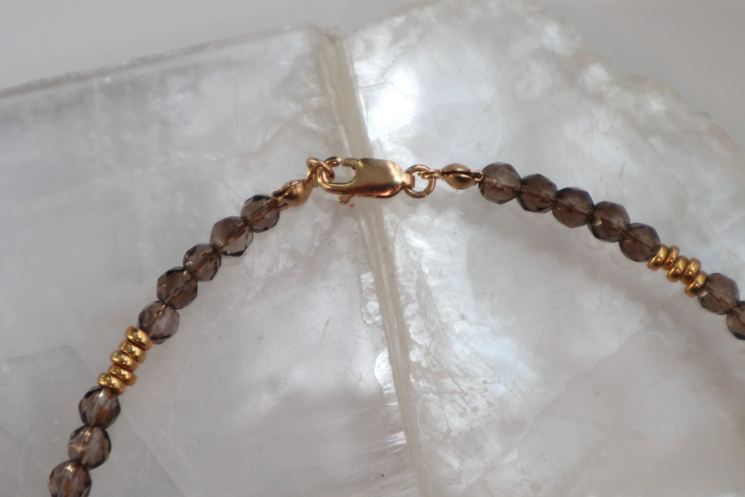 Detail shot of the Mira necklace showing the 14k gold-filled clasp and the natural color variation and translucency of smoky quartz beads with galvanized gold spacers