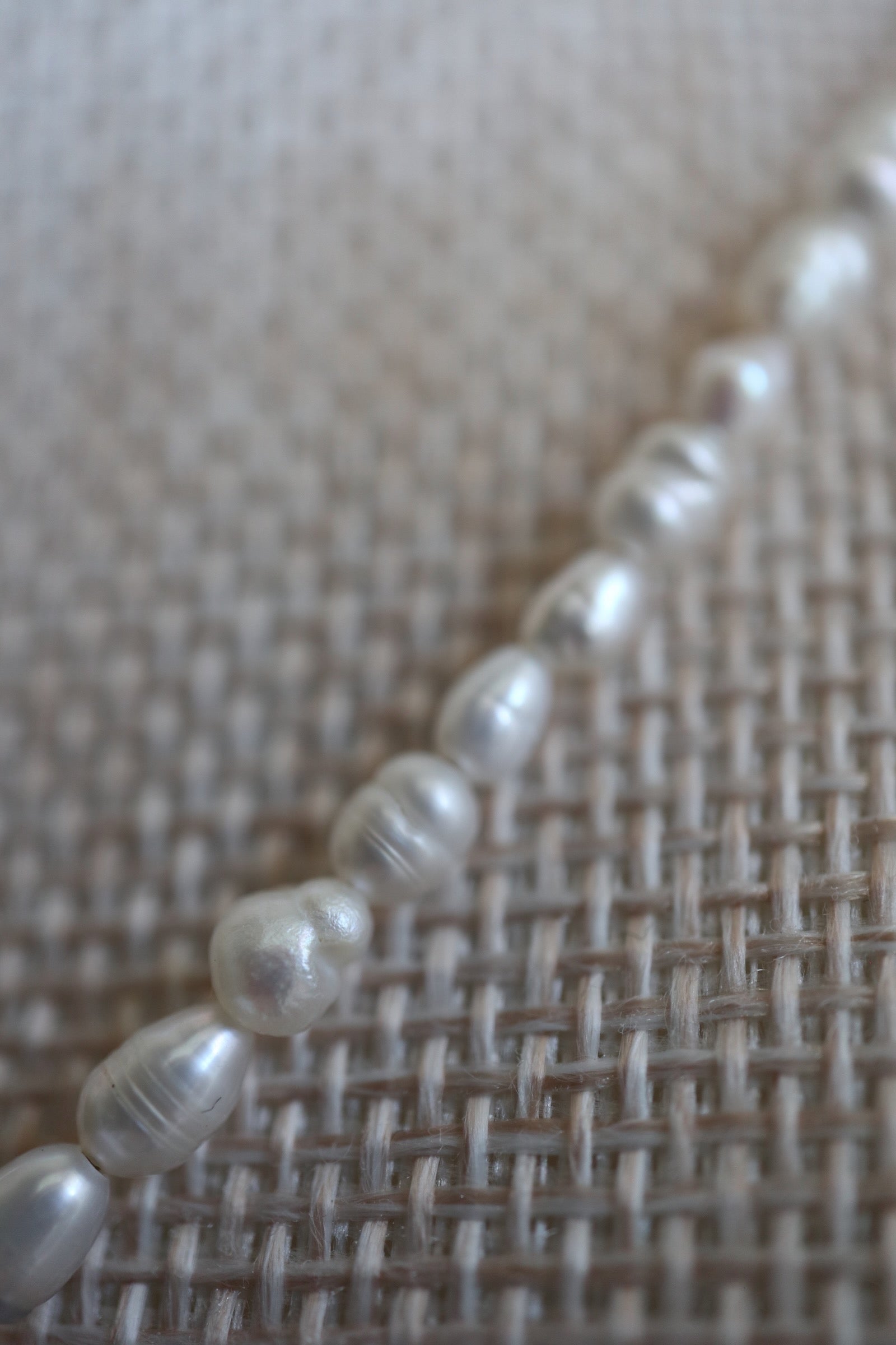 Auréad Designs Nacrine necklace close-up showing grade 5A freshwater rice pearl texture and natural luster, photographed on linen bust form