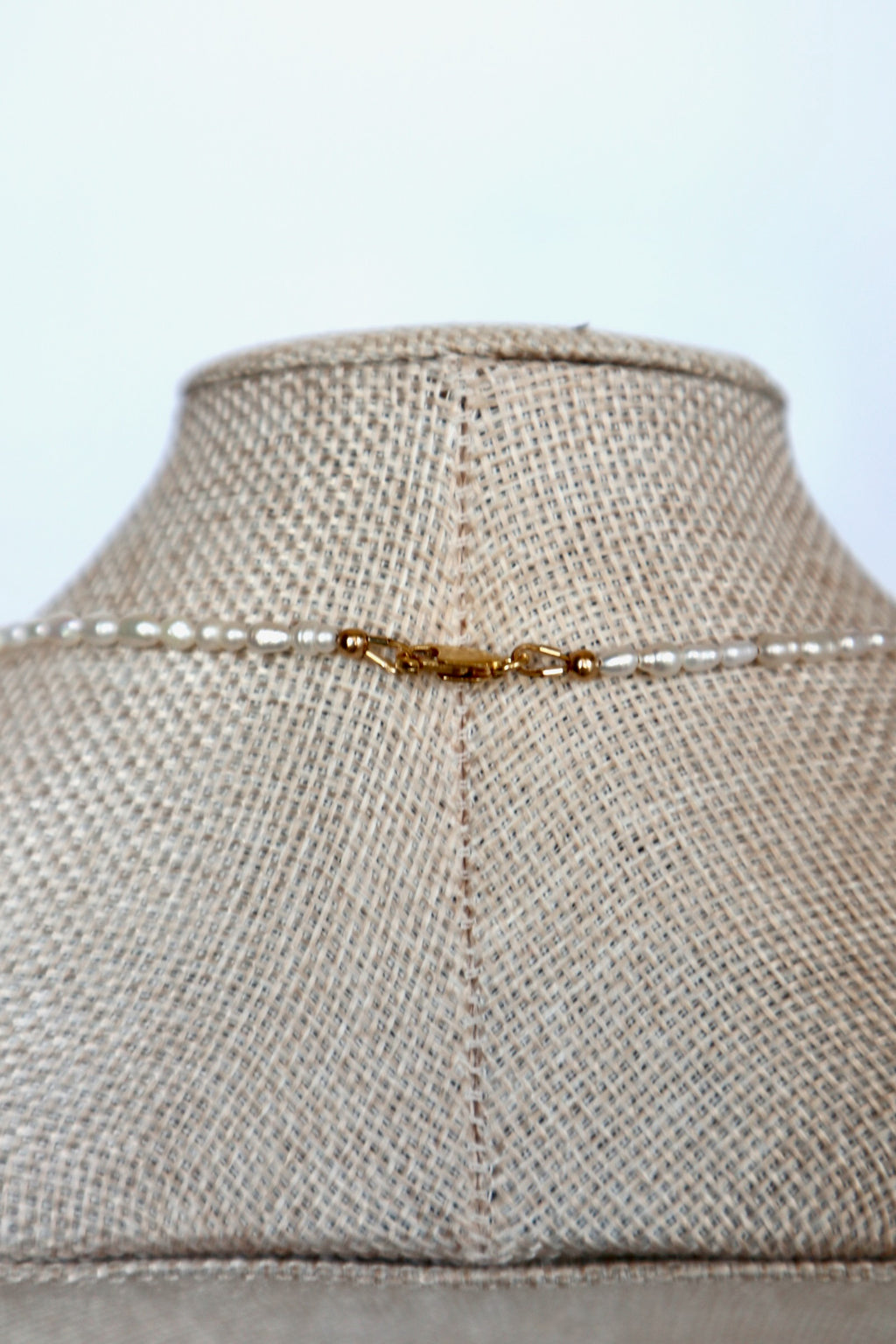 Auréad Designs Nacrine necklace back clasp detail showing 14k gold-filled lobster clasp with freshwater rice pearl strand on linen bust form